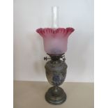 An oil lamp with ceramic body and glass font with cranberry tinted shade, 58cm tall, some usage wear