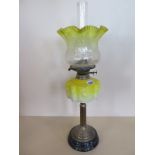 An oil lamp with yellow moulded glass font and yellow tinted shade, 65cm tall, overall good