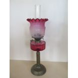 An oil lamp with cranberry font and tinted shade, 67cm tall, good condition, some wear to base