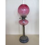 An oil lamp with cranberry glass font and cranberry globe shade, 73cm tall, minor chips to base of