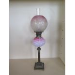 An oil lamp with etched cranberry tinted globe shade and pink glass moulded font - 71cm tall,