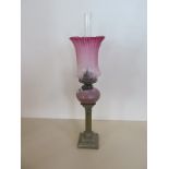 A pipe oil lamp with cranberry etched shade and white and pink reservoir, 51cm tall, small chip to