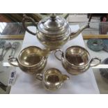 A silver teapot, a sugar bowl, milk jug and cream jug, hallmarked London 1911, some dents and