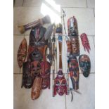 A collection of tribal items including large and small carved wooden masks, largest 58cm long,