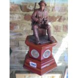 A commemorative figurine of a WW1 British soldier with six pennies to its wooden plinth,