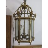 A brass framed, hall lantern with glass panels arranged in hexagonal form, with electric lights,