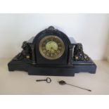 A black slate striking mantle clock with lion details - 57cm wide with pendulum and key