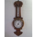 An carved oak case aneroid barometer with 5 inch white ceramic dial, approximately 59cm high, in