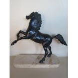 A bronzed figurine of a stallion raised upon a marble base, approximately 53cm high overall 47.5cm