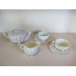 A Belleek shell teapot, milk jug, cup and saucer with another cup and saucer, all good except one