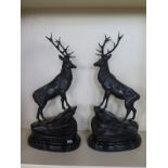 A pair of modern large bronze stags standing on rocky outcrops on oval marble bases, in the style of