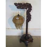 A 1930's Chinese wooden table lamp in the form of a dragon with the lamp hanging from the dragons