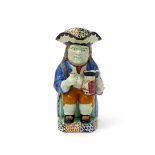 A Mexborough (Yorkshire) or Crown mark Toby jug, early 19th century, resting a miniature standing