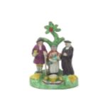 A Staffordshire Tithe Pig figure group, c.1820, a couple standing beneath a tree with a clergyman