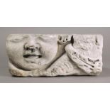 A Medieval marble fragment carved a rotund face with an open mouth, with a leaf and drape