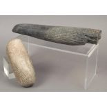 Two sacred stones one of tapering cylindrical form with an area of carved hatching, the larger end