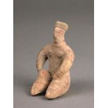 A Tel Halaf terracotta male idol circa 4th Millennium BC seated, wearing a headdress with painted