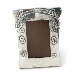 An Art Nouveau silver photograph frame, on wooden mount with easel back, cast in low relief with