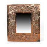 An Arts and Crafts copper wall mirror, rectangular, stamped in low relief with a frieze of acorns