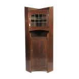 A Liberty & Co oak corner cupboard, architectural form, the panelled door below glazed door upper