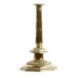 A large late 17th century sheet brass candlestick, repoussé decorated, with a fluted nozzle, above