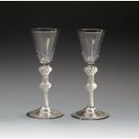 A near pair of small wine glasses, c.1760, with rounded funnel bowls raised on double knopped