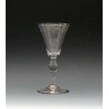 A wine goblet, c.1730-40, the generous funnel bowl engraved around the rim with a formal foliate
