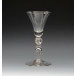 A light baluster glass, c.1720-30, the bell bowl above a ball knop enclosing a row of tears over a