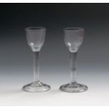 A pair of small wine glasses, c.1760, with rounded funnel bowls, raised on plain stems above