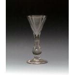 A baluster wine glass, c.1720, the drawn trumpet bowl rising from a plain baluster stem enclosing