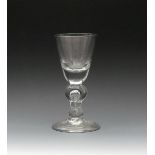 A heavy baluster glass, c.1710, the rounded funnel bowl rising from a double-knopped baluster stem