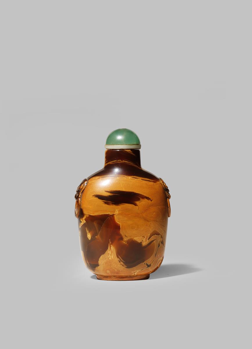 A CHINESE AMBER SNUFF BOTTLE 19TH CENTURY With a flattened circular body with lion mask handles to