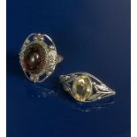 A silver ring, the pierced frame with foliate motif, set with modelled ruby glass panel, and a