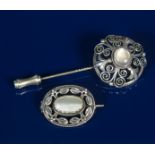 A silver brooch, elliptical form pierced and cast with foliate border and set with central mother of