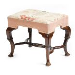A George I walnut stool, the later gros and petit point needlework seat depicting a prosperous