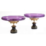 A pair of Victorian amethyst glass and gilt bronze tazze, each with a shallow bowl, with a rosette