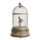 An early 20th century French brass musical automaton singing bird, perched on a bar in a birdcage,