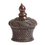 A treen turned and carved nutmeg box and cover, the lid decorated with leaves above a basket base,