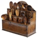 A George III oak wall hanging spoon rack, with a shaped raised back and three tiers pierced with