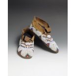 A pair of Cree moccasins buckskin and coloured glass beads, fully beaded with a white ground and