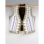 A Northern Plains vest circa 1900, canvas, cloth and beads, the front panels with a white ground and