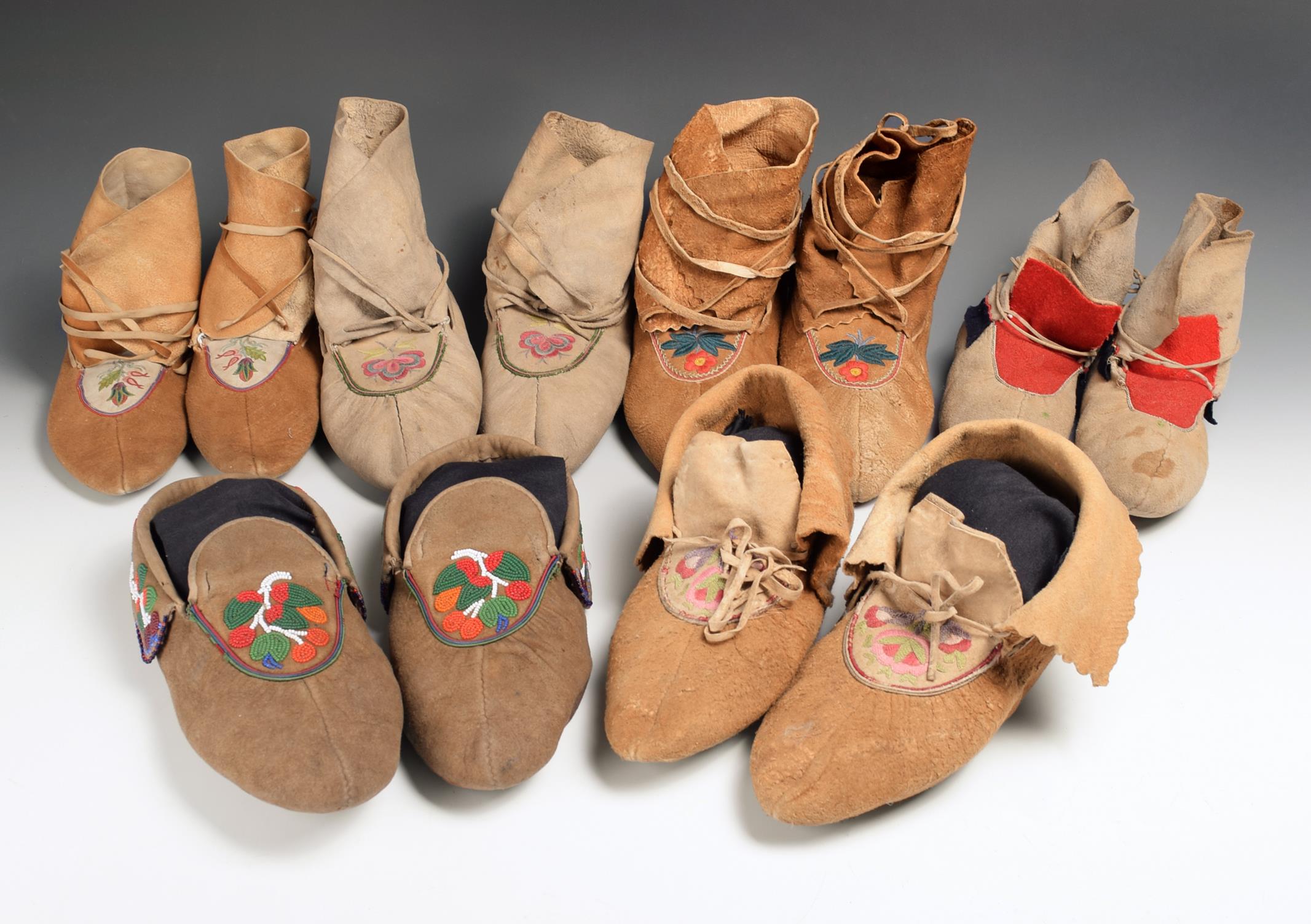 Six pairs of Chippewa moccasins with puckered toes, including four pairs with floral embroidered