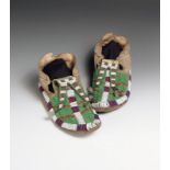 A pair of Dakota moccasins buckskin, coloured glass beads, tin cones and feathers, with green,