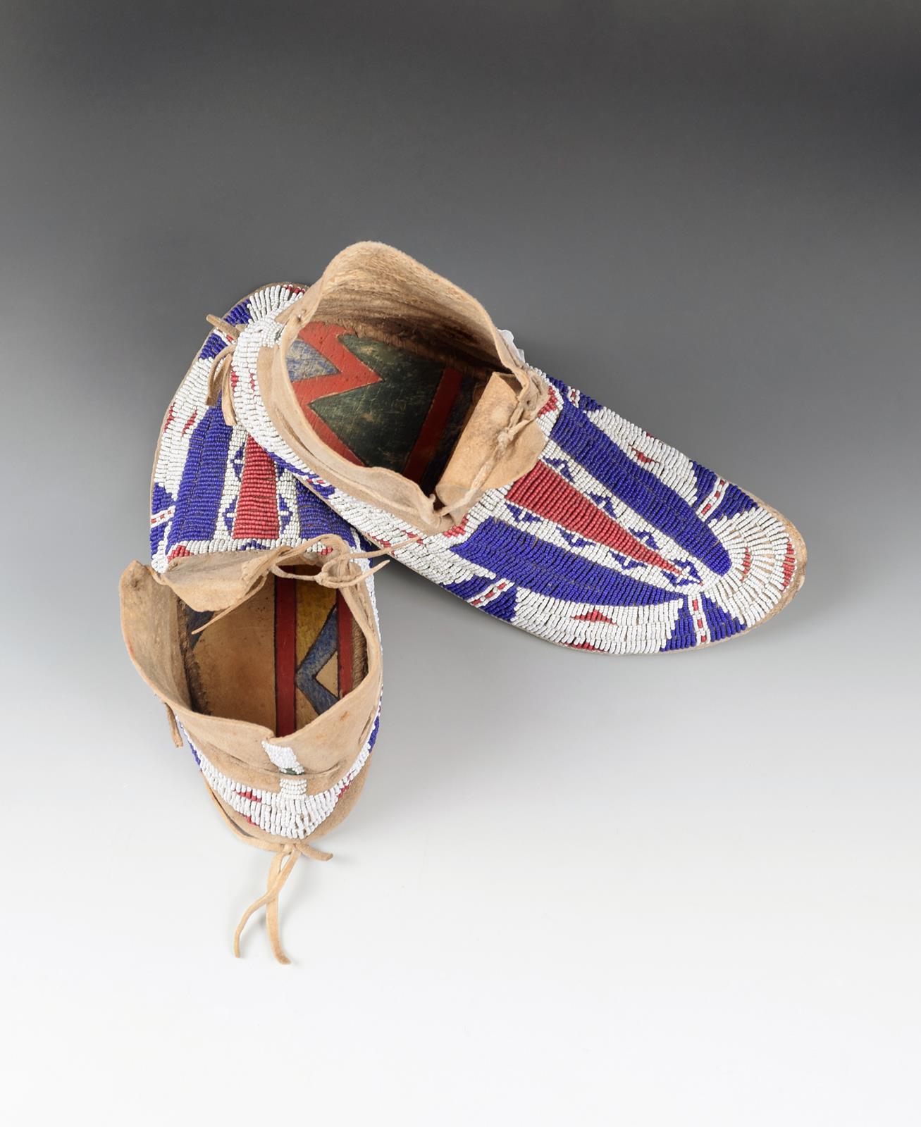 A pair of Cheyenne moccasins buckskin, coloured glass beads, fully beaded in white, red and blue,