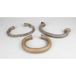 Three West African currencies brass and copper, including a King manilla, 30cm wide, one twisted and