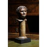 A glazed pottery Grand Tour bust of the Roman Emperor Titus, wearing a laurel wreath, mounted on