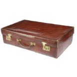 An early 20th century crocodile leather suitcase by Army & Navy, the hinged lid with gilt