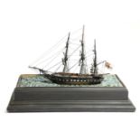 An early 20th century model three-masted sailing ship, painted wood, with a metal canon, flying