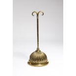 A Victorian brass doorstop, with a scroll handle and a lobed bell shaped weighted base, stamped with