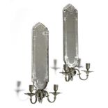 A pair of 18th century style wall sconces, each with a cut mirrored back, above a pair of bronze